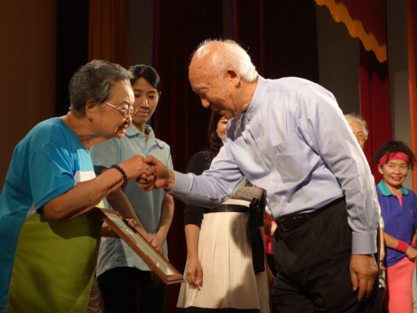 彩霞教育基金會董事長陳哲宏於2015年「微笑樂齡嘉年華」活動頒發感謝狀給仁濟安老所百歲長輩代表。（彩霞教育基金會提供）